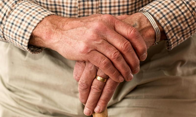 Ingezoomde foto van de handen van een oudere man die een stok vasthoudt